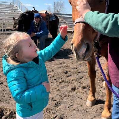 Little girl thanking horse for letting her ride him